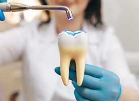 Dentist hardening sample dental bonding on model tooth with UV light