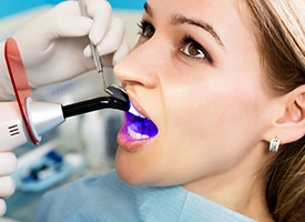 Dentist applying UV light to woman’s dental bonding