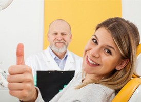A smiling woman at the dentist’s office giving a thumbs up