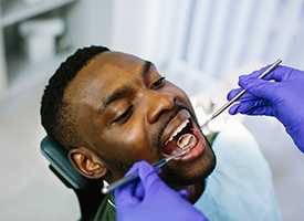 Dentist using dental mirror to examine patient's teeth
