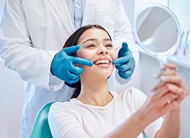 Woman smiling while looking at reflection in handheld mirror