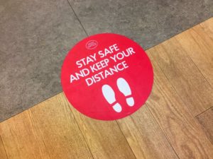 Sign on floor asking visitors to practice social distancing