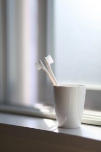 Two toothbrushes in white cup