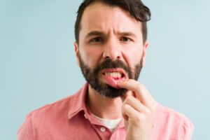 Man pulling down lower lip to reveal red gums.